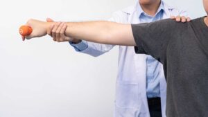 A local adult performing gentle knee stretches with a physical therapist in a bright clinic setting.